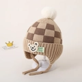Detail van gebreide muts met dambordpatroon voor peuters met beer-patch en pompon - Donker Kaki Schaakbord Beer Stijl / Donker kaki