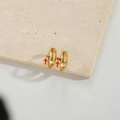 Minimalist gold hoop earrings with red cross design on a neutral stone background - Red