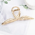 Elegant gold metal hair claw clip with wing leaf design on white marble surface - Linear Wing Shape Gold B3323