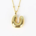 Close-up of polished gold 3D balloon initial U pendant with fine link chain necklace - Letter U