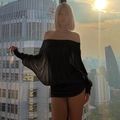 Detail of off-shoulder ruched black dress with long sleeves in a backlit urban setting - S / Dresses / Black