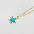 Starfish pendant necklace with sky blue enamel on a golden fine chain over white texture - Lake Blue