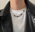 Titanium stalen ketting met spin- en sterhangers over een zwart leren motorjack - Ketting Met Kralen In De Vorm Van Een Spinnenvierpuntster