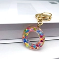 Macro detail of clear resin letter O keychain with colorful heart sequins and gold clasp - Letter O Lobster Clasp Keychain