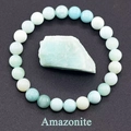 Macro view of amazonite beaded bracelet with raw gemstone piece on grey background - Amazonite
