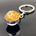 Solar system sun galaxy glass ball keychain with silver metal ring on reflective surface - Sun