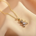 Detailed close-up of a gold teddy bear pendant necklace with heart-shaped gemstone - White Zircon