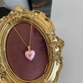 Detail of pink enamel heart pendant with a small gold heart set in an ornate vintage frame - Pink