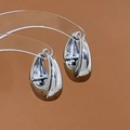 Macro shot of silver teardrop hoop earrings on clear stands with high-polish finish - Silver