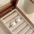 Vista macro de pendientes de botón con perlas blancas grandes en caja de madera - 14mm