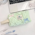 Dettaglio dell'astuccio trapuntato verde chiaro con fiocchi e cancelleria sulla scrivania - Quadretti Verde Frutta