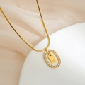 Macro detail of gold oval pendant with zircon halo and letter W on snake chain - Letter W