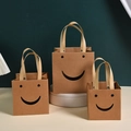 Brown kraft gift bags with smiley face cutout and reinforced handles in three sizes - Kraft Smile