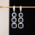 Primer plano de pendientes colgantes de tres niveles de circón azul con halo de pavé - Azul Real