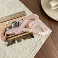 Macro shot of large pink iridescent heart hair claw clip on a magazine and wooden desk - Metallic Pink
