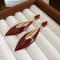Detail of red enamel water drop earrings with golden edges on a jewelry box background - Red
