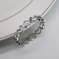 Macro shot of silver hollow heart napkin ring resting on a white ceramic plate edge - Silver