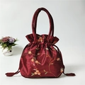 Detail showing the burgundy silk texture and floral embroidery on the drawstring bucket bag - Burgundy