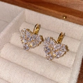 Detailed close-up of heart-shaped gold earrings with white zircon crystals on velvet box - White Zirconia Heart Style / Gold