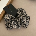 Detailed view of floral print scrunchie with a black brand tag on soft fabric - 1# Large White Black Flower