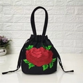 Détail de broderie de roses rouges sur un petit sac seau noir avec cordon de serrage - Rose Rouge