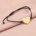 Detail of a golden heart charm on a black braided cord against a pink silk background - 18K Gold (MP060)