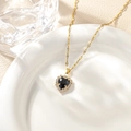 Macro shot of a heart pendant necklace with black core and diamonds on a white ceramic tray - Black Pendant And Necklace