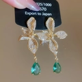 Vista macro di orecchini floreali placcati oro 18k con zirconi e pendente a goccia verde - Oro (con pietra verde)