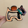Vue détaillée d'une pince à cheveux en acétate motif Terrier écossais tenue en main - Forme de Chien Noir-Marron
