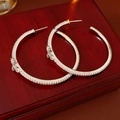 Dettaglio di orecchini a cerchio in argento con zirconi e ciondoli a croce su legno - Argento (Perno in argento) / Argento