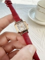 Close-up of a women's red leather square watch with a gold-tone dial and numerals - Red