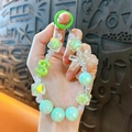 Vibrant mint green beaded phone strap featuring a dollar sign and translucent bow charm - Green