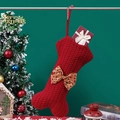 Red knit bone-shaped Christmas stocking with brown bow hanging on a festive tree - Knitted Bone Stocking / Red