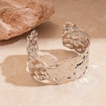 Close-up of silver wide open cuff bracelet featuring an irregular hammered metal texture - Silver