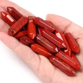 Macro shot of polished red jasper hexagonal crystal pillars held in hand for scale - Red Jasper