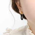Pendientes en forma de U de acero inoxidable negro y dorado en una modelo - Negro