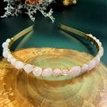 Macro detail of handmade gold wire-wrapped pink crystal bridal crown on wood base - Rose Quartz with Gold Headband and Gold Wire
