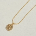 Gouden Gemini-sterrenbeeldketting met witte zirkonia op getextureerde beige achtergrond - 2 Figuren