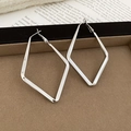Close-up of silver geometric rhombus pendant hoop earrings on a velvet jewelry tray - Silver - Large