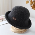Elegant dark grey wool bucket hat with brown BRUHT embroidery patch on a wooden stand - Dark Gray
