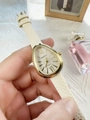Detailed close-up of a teardrop-shaped gold watch with a white textured leather strap - White (59167)