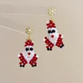 Close-up of handmade beaded Santa Claus earrings with golden snowflake hooks - Snowflake Santa Claus-Silver Pin / Stud Earrings