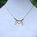 Collar de pareja dorado con colgantes de niño, niña y corazón en soporte de joyas - Dorado