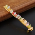 Detailed macro view of colorful natural crystal stones hand-wrapped on a golden metal hair clip - Colorful Crackle Quartz + Gold Clip
