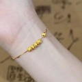 Primo piano della collana in oro con cinque perle sabbiate su una catena sottile - Bracciale con sfere d'oro portafortuna