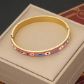 Dettaglio macro del bracciale vintage in acciaio inossidabile dorato con motivi a occhi - Occhi Rosa e Blu (2#)