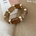 Vista macro de los segmentos de resina ámbar dorado y piezas metálicas en el brazalete - Café Claro