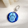 Makro-Detail von Hamsa und Evil Eye Muster auf rundem Schlüsselanhänger mit Silberclip - Blaues Porzellan Stil Hamsa Hand