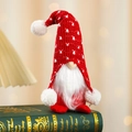 Cozy Christmas gnome with red knitted hat sitting on books in warm holiday light - Red