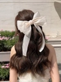 Oversized cream organza bow hair clip with long ribbons shown on model's hair - Beige